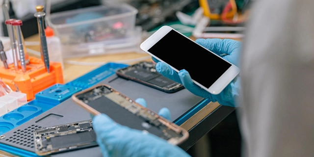 Someone holding the exposed inside of a cell phone and a phone screen