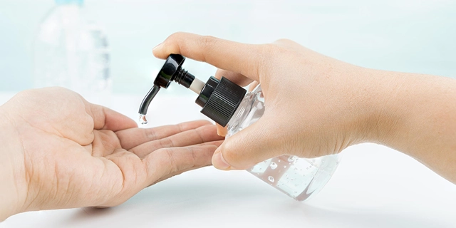 A person dispensing liquid clear soap on their hands